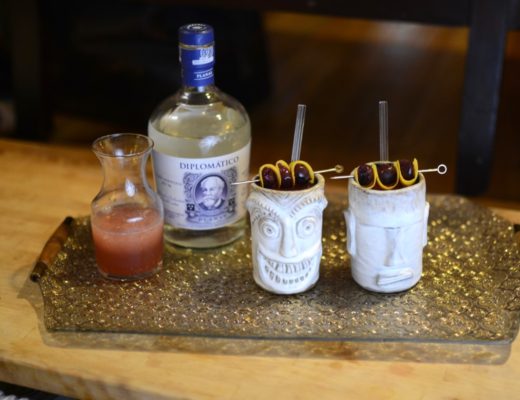 two handmade tiki mugs on a gold tray with a bottle of diplomatico white rum