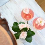 two coupe glasses with margaritas and rose garnishes