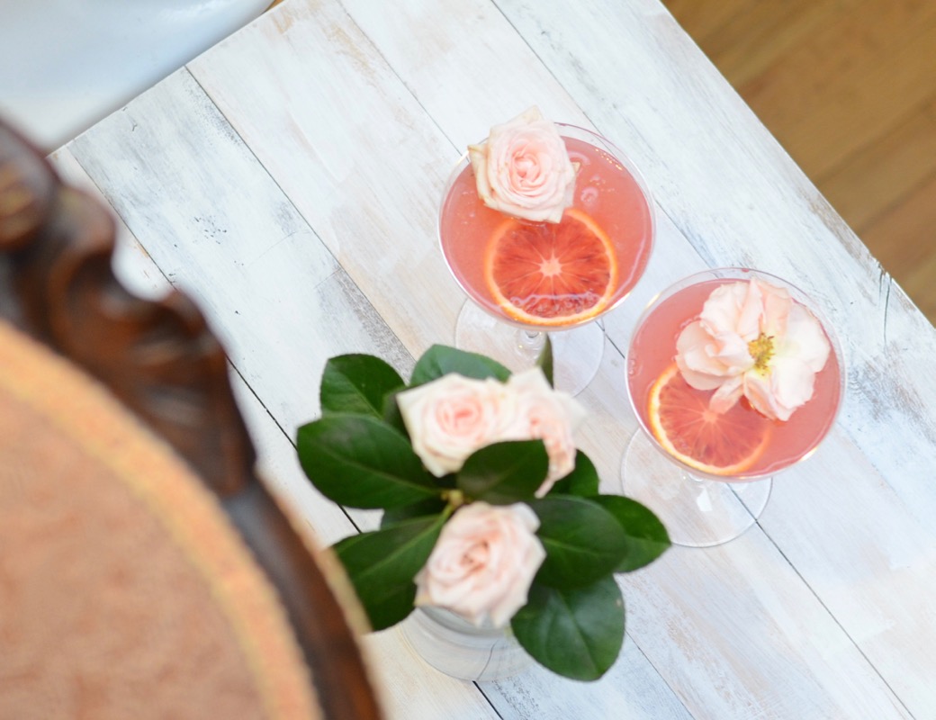 two coupe glasses with margaritas and rose garnishes