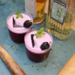 two purple cocktails with a blackberry and mint garnish