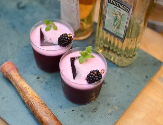 two purple cocktails with a blackberry and mint garnish