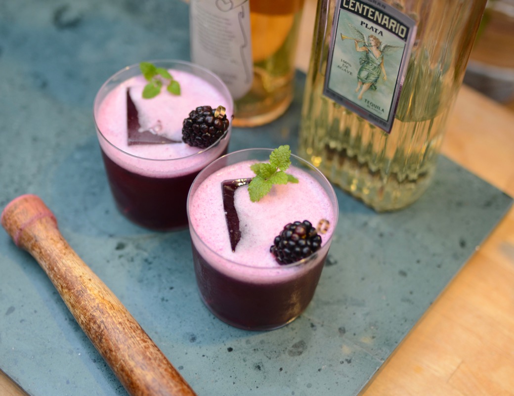 two purple cocktails with a blackberry and mint garnish