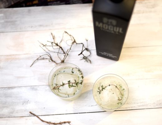 Two cocktails on a white board with thyme sprigs