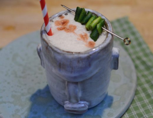 cocktail with a lime garnish in a handmade tiki mug