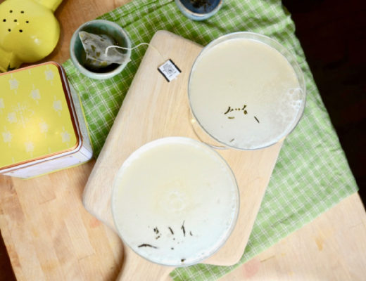 cocktail made with tea with a lemon strainer and tea bag in corner