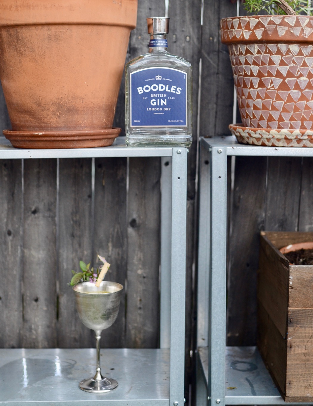 boodles gin bottle with a cocktail in a silver goblet outside