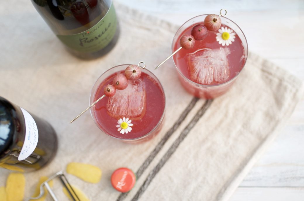 two pink cocktails with gooseberries and chamomile flower